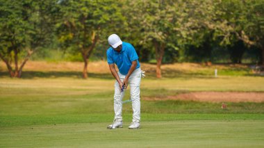 Golfer putting ball on the green golf, lens flare on sun set evening time, Golfer action to win after long putting golf ball in to the hole,