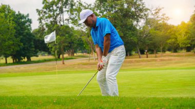 Akşam golf sahasında golf oynayan bir golfçü. Güneşin altında golf oynayan bir adam..