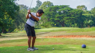 Akşam golf sahasında golf oynayan bir golfçü. Güneşin altında golf oynayan bir adam..