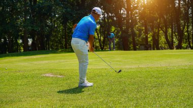 Golfer playing golf in the evening golf course, on sun set evening time, Man playing golf on a golf course in the sun.