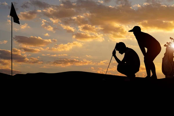 在日落时分 高尔夫球手将高尔夫球打向洞口 勾勒出轮廓 冬日的清晨 朦胧的高山背景 — 图库照片