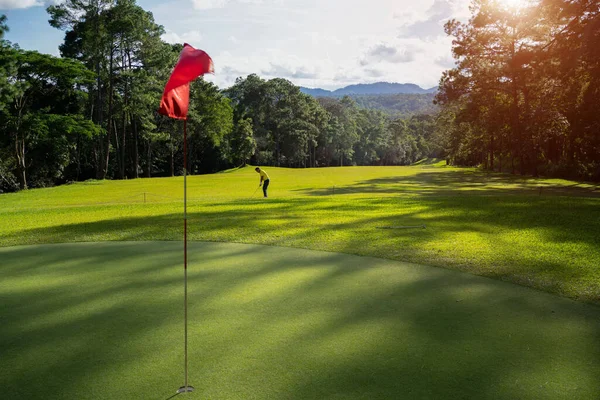 ブルーゴルファーは 緑のゴルフにボールを入れて 太陽のセット夜の時間にレンズフレア — ストック写真