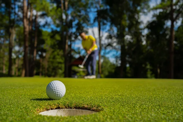 模糊的高尔夫球手在傍晚高尔夫球场打高尔夫球 日落时分 高尔夫球手正在把高尔夫放在晚上的高尔夫球场上 体育假日生活方式概念 图库图片