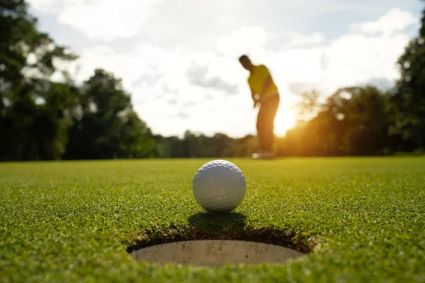 夜のゴルフコースでゴルフをプレイするぼやけたゴルファー 日没の夜の時間に ゴルファーは夕方のゴルフコースにゴルフを入れている スポーツホリデーライフスタイルコンセプト ロイヤリティフリーのストック画像