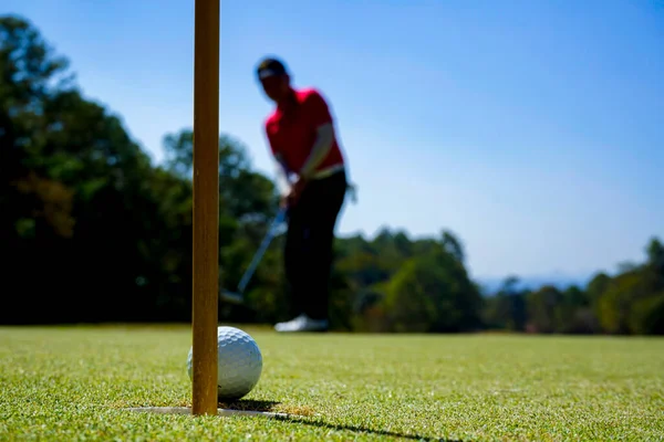 高尔夫球手把球放在绿色的高尔夫球上 夕阳西下时镜头闪现 高尔夫球手把高尔夫球打进洞里很长时间后 打高尔夫球获胜的动作 — 图库照片