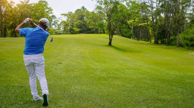 Akşam golf sahasında golf oynayan bir golfçü. Güneşin altında golf oynayan bir adam..                                