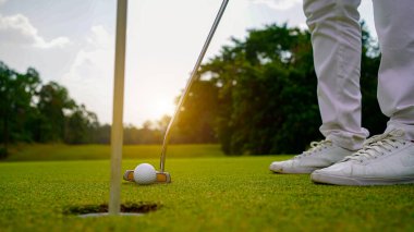 Golf topları gün batımında golf sahasında golf oyuncuları tarafından delik deşik edilecek. Golfçüler akşam saatlerinde golf sahasına golf oynuyorlar..                                