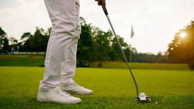 Golf topları gün batımında golf sahasında golf oyuncuları tarafından delik deşik edilecek. Golfçüler akşam saatlerinde golf sahasına golf oynuyorlar..                                