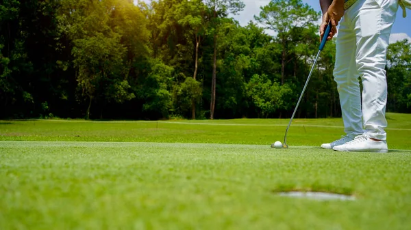 夕日の緑の芝生のゴルフコースでゴルファーによって穴になるだろうゴルフボール ゴルファーは夕方のゴルフコースにゴルフを入れています 日没の夜の時間に — ストック写真