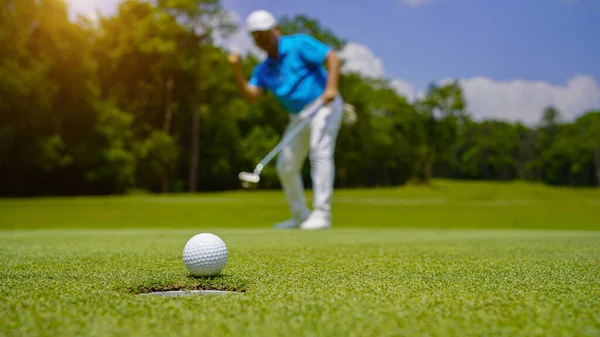 緑のゴルフにボールを入れてゴルファー 太陽の下でレンズフレアは夜の時間を設定します 長い穴にゴルフボールを入れて後に勝つためにゴルファーのアクション ロイヤリティフリーのストック写真