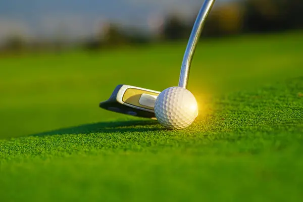 朝の日差しで美しいゴルフコースで緑のゴルフボールとゴルフクラブ 最初のショートでゴルフの準備 ストック写真