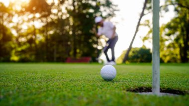 Bulanık golfçü akşam vakti golf sahasında golf oynuyor. Güneşin altında golf oynayan bir adam..                                
