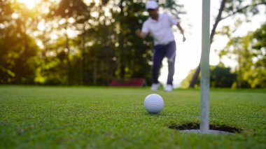 Bulanık golfçü akşam vakti golf sahasında golf oynuyor. Güneşin altında golf oynayan bir adam..                                