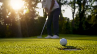 Bulanık golfçü akşam vakti golf sahasında golf oynuyor. Güneşin altında golf oynayan bir adam..                                