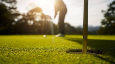 Bulanık golfçü akşam vakti golf sahasında golf oynuyor. Güneşin altında golf oynayan bir adam..                                