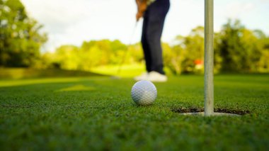 Bulanık golfçü akşam vakti golf sahasında golf oynuyor. Güneşin altında golf oynayan bir adam..                                