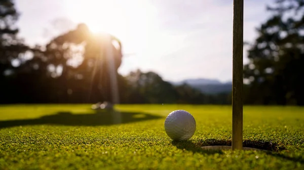夜のゴルフコースでゴルフをプレイするぼやけたゴルファー 日没の夜の時間に 太陽の下でゴルフコースでゴルフをしている男 ロイヤリティフリーのストック画像