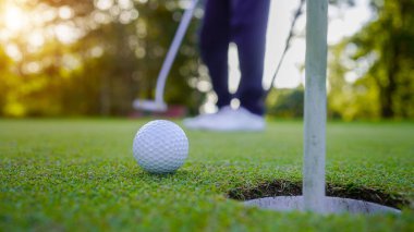 Akşam golf sahasında golf oynayan bir golfçü. Güneşin altında golf oynayan bir adam..                               