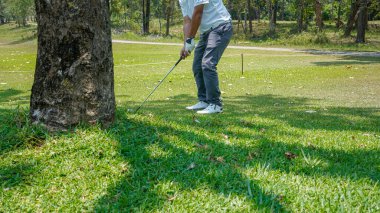 Golfçü golf oynuyor ve yeşil çimen dağ arka planına vuruyor. Asya 'lı erkek oyuncu yazın vuruldu. Spor tatil yaşam tarzı konsepti.                               