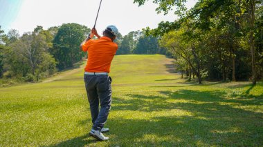 Golfçü golf oynuyor ve yeşil çimen dağ arka planına vuruyor. Asya 'lı erkek oyuncu yazın vuruldu. Spor tatil yaşam tarzı konsepti.                               