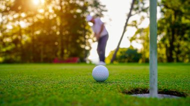 Golfçüler golfü akşam golf sahasına koyuyorlar. Golfçü golf topuna vuruyor. Spor tatil yaşam tarzı kavramı.                               