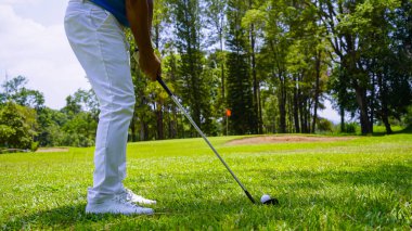 Golfçüler akşam golf sahasında golf oynuyorlar. Golfçü golf topuna vuruyor.                                