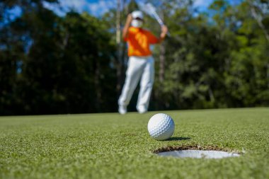 Akşam golf sahasında golf oynayan bir golfçü. Güneşin altında golf oynayan bir adam..                                