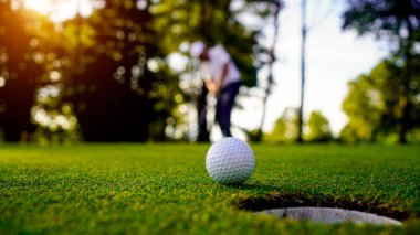 Golfçüler golfü akşam golf sahasına koyuyorlar. Golfçü golf topuna vuruyor. Spor tatil yaşam tarzı kavramı.                                