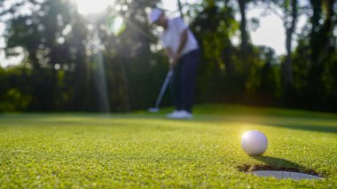Golfçüler golfü akşam golf sahasına koyuyorlar. Golfçü golf topuna vuruyor. Spor tatil yaşam tarzı kavramı.                                