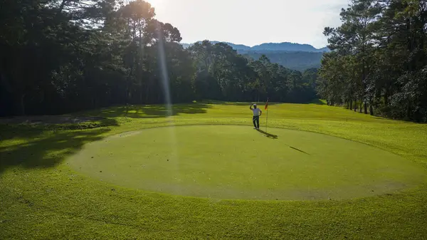 Golfçüler golfü akşam golf sahasına koyuyorlar. Golfçü golf topuna vuruyor. Spor tatil yaşam tarzı kavramı.                                