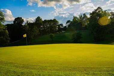 Güneşli bir günde güzel bir golf sahası. Arka plandaki golf sahasında güneş ışığı parlıyor. Kırsaldaki golf sahasında..