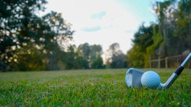 Golf sopaları ve golf topları yeşil çimlerde sabah güneşli güzel bir golf sahasında. Yeşil çimlerde golf ekipmanlarını kapatın..                                