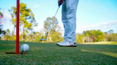 Blurred Golfer putting ball on the green golf, lens flare on sun set evening time. Golfer hitting golf ball. Sport holiday lifestyle Concept.                               