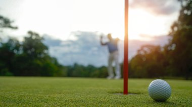 Golfçüler golfü akşam golf sahasına koyuyorlar. Golfçü golf topuna vuruyor. Spor tatil yaşam tarzı kavramı.                               