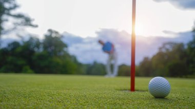 Golfçüler golfü akşam golf sahasına koyuyorlar. Golfçü golf topuna vuruyor. Spor tatil yaşam tarzı kavramı.                               