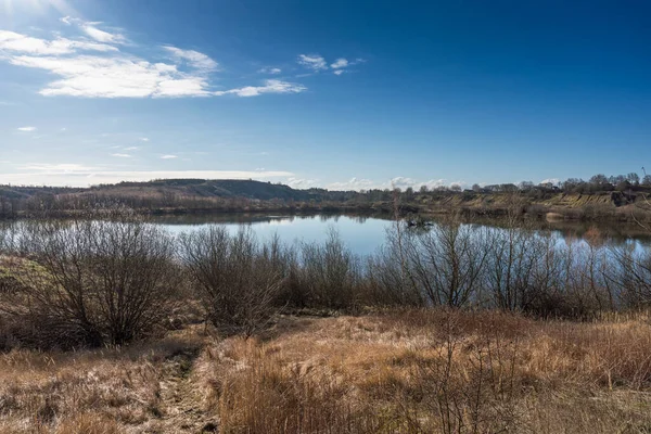 stock image View over a landscape with small hills and lake created in a closed gravel pit in early spring Denmark