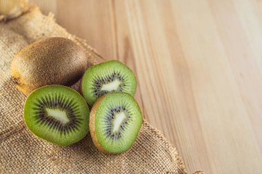 Ahşap arka planda kivi meyvesi. Tamamı ve parçaları. Boşluğu kopyala