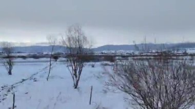 Arkasında dağlar ve bulutlar olan engin karlı bir tarla..