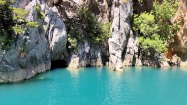 Parlak mavi bir nehirde, kayalık bir kıyıda seyahat ediyor. 