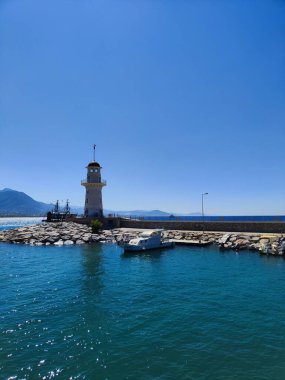 Deniz feneri kayalık kıyılarda ve berrak mavi su parlak güneş ışığında