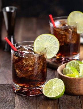 Kırsal ahşap masada limon dilimli rom ve kola kokteyli.