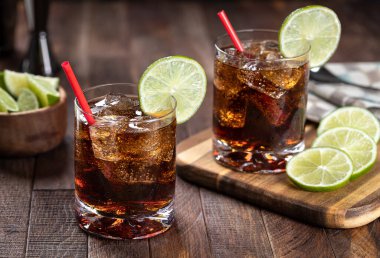 Kırsal ahşap masada limon dilimli rom ve kola kokteyli.