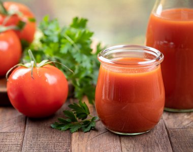 Bardakta domates suyu taze domatesli sürahi ve ahşap masada maydanoz. 