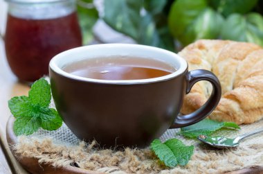 Nane yaprağı, kruvasan ve çuval bezli bir kavanoz reçelli çay.