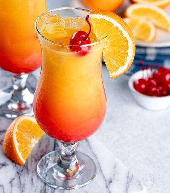 Mermer masada kiraz ve portakal dilimli tekila gündoğumu kokteyli.