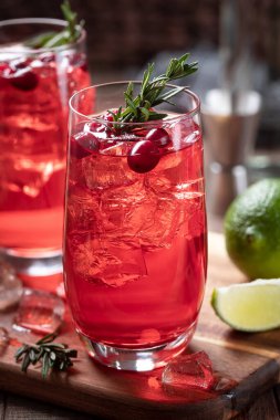 Limon dilimli kızılcık kokteyli ve ahşap masada biberiyeyle süslenmiş.