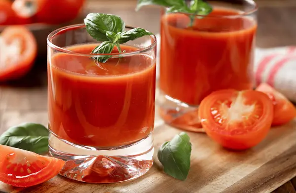 两杯番茄汁加罗勒叶 把西红柿片放在木桌上 免版税图库图片