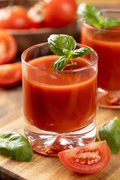 两杯番茄汁加罗勒叶 把西红柿片放在木桌上 图库图片