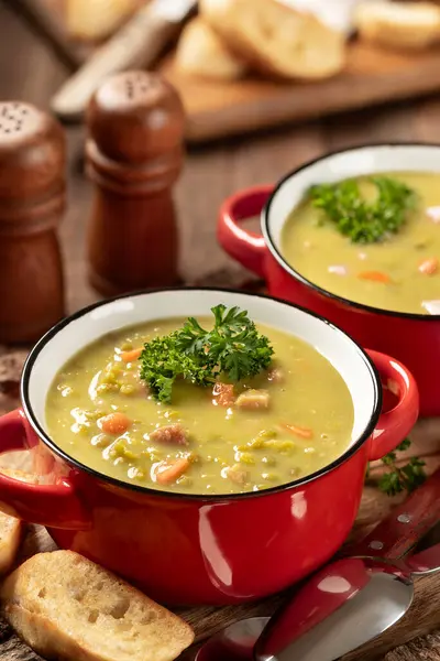 两碗豌豆汤配火腿和胡萝卜 用香菜装饰在乡村木盘上 图库图片