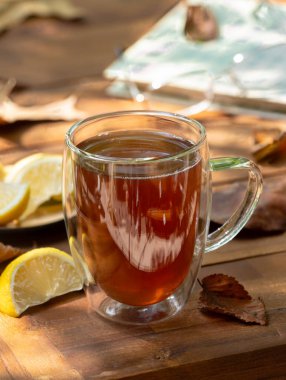 Sonbahar yapraklı, kitaplı ve bardaklı, limon dilimli bir bardak çay.